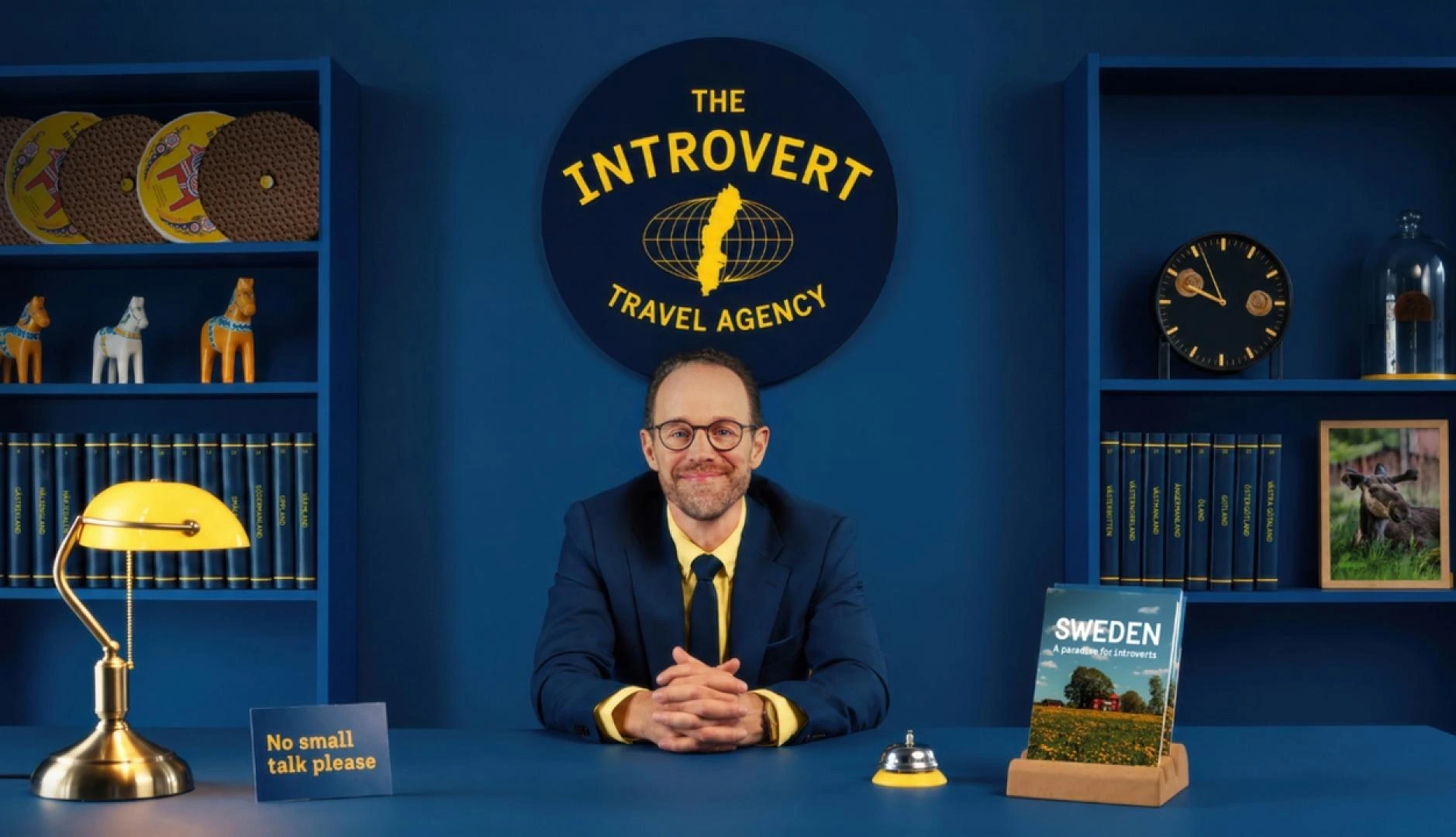 Tienda temporal de The Introvert Travel Agency de Visit Sweden con sombrillas amarillas y el logo de la agencia
